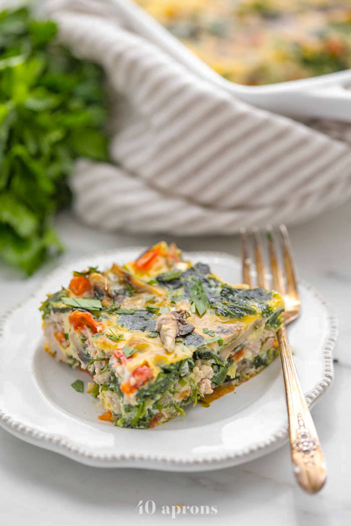 A square of Whole30 sausage, spinach, and mushroom breakfast casserole on a plate.