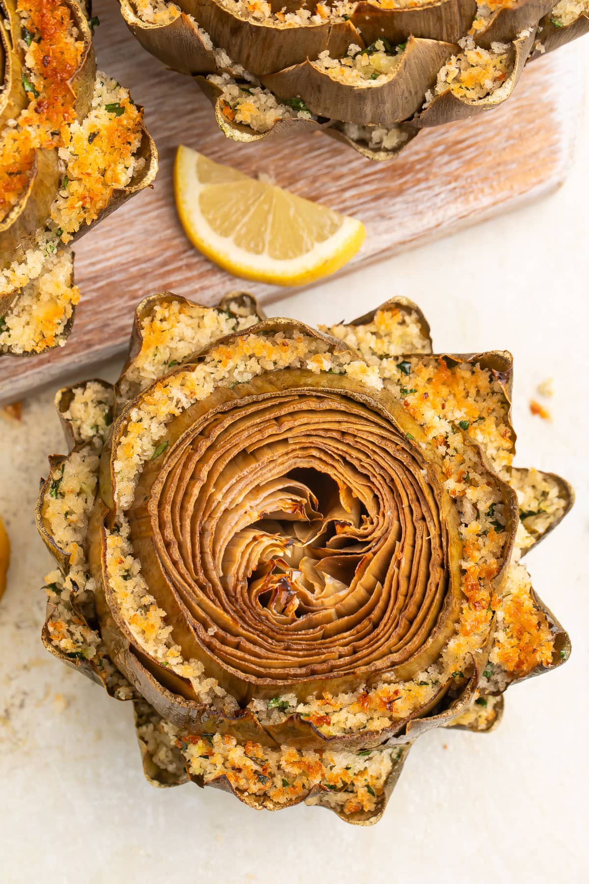 Top-down look at a stuffed artichoke, with breadcrumb stuffing packed between each row of petals and baked until golden.