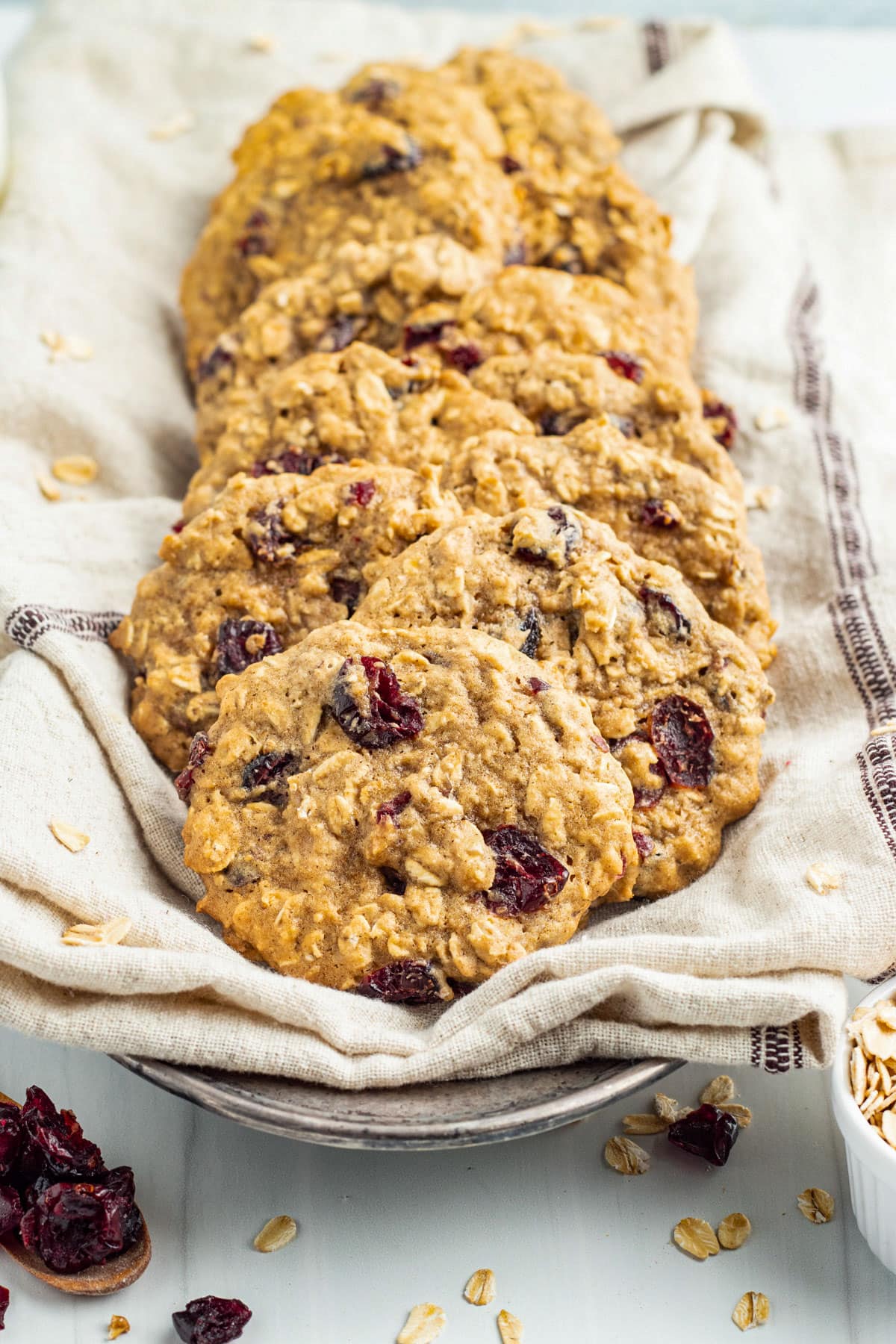 Oatmeal cranberry cookies arranged on a shallow plate lined with a cloth napkin.