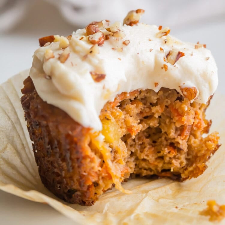 A carrot cake cupcake topped with white frosting.
