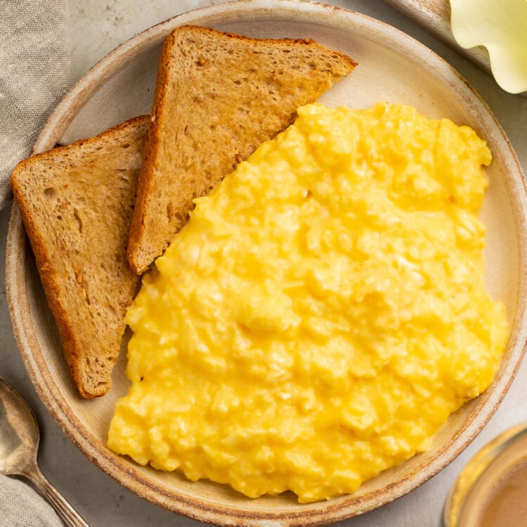 Mom's favorite cheesy scrambled eggs on a plate with two triangular slices of toast.