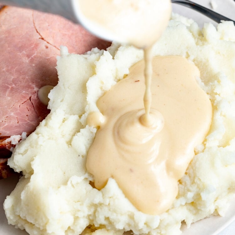 Ham gravy being poured over mashed potatoes.