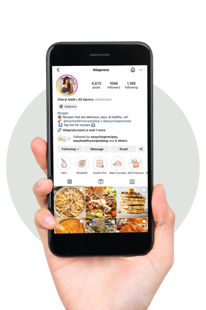 A hand holding a smartphone displaying the 40 Aprons Instagram page.