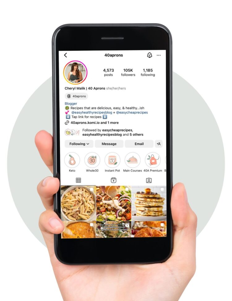 A hand holding a smartphone displaying the 40 Aprons Instagram page.
