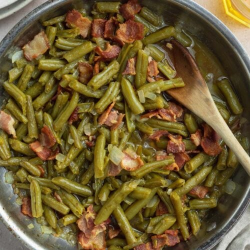 Texas Roadhouse green beans with bacon and onions in a large silver skillet.