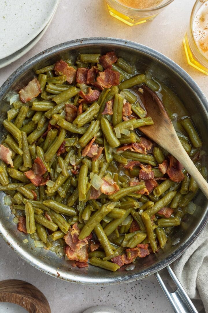 Texas Roadhouse green beans with bacon and onions in a large silver skillet.