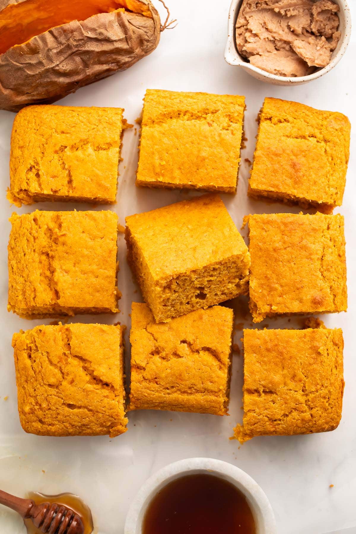 9 squares of sweet potato cornbread lined up on a table in 3-by-3 square.