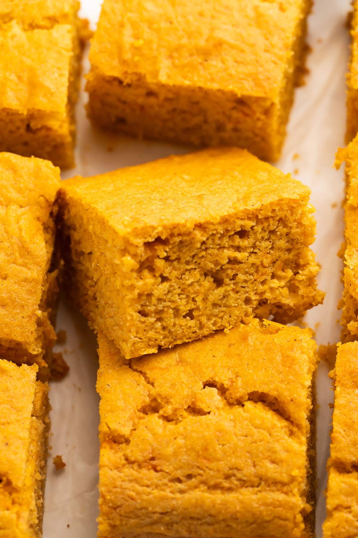 Close-up of a piece of sweet potato cornbread resting atop another piece of cornbread to better show the inside texture of the bread.