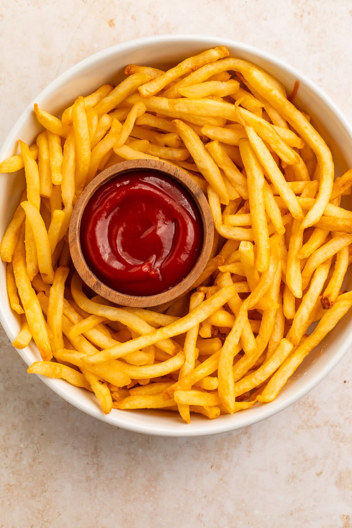 Crispy air fryer french fries arranged on a white plate with ketchup dipping sauce.