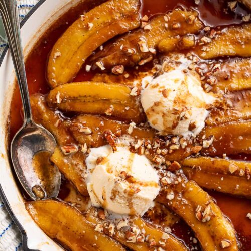 Rich bananas foster topped with scoops of vanilla ice cream in a large pan.