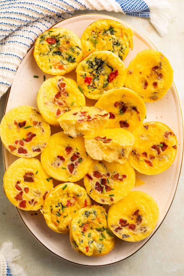 An oval platter with muffin-shaped egg bites made with cottage cheese, bacon, and veggies.