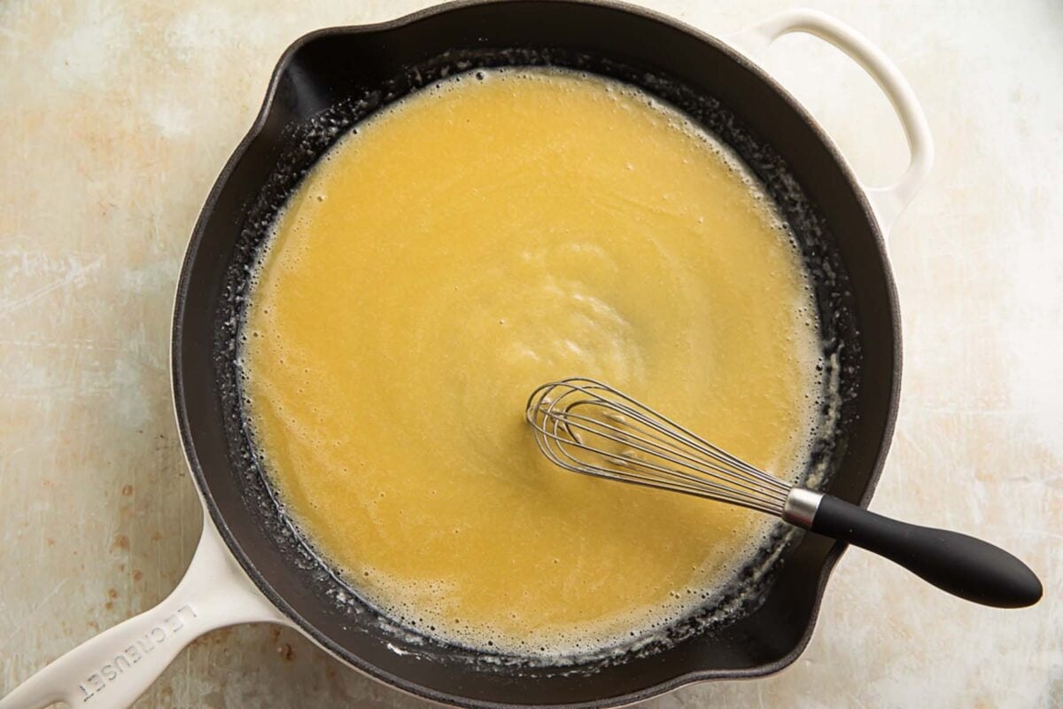 A rich, blonde roux in a large skillet with a whisk.