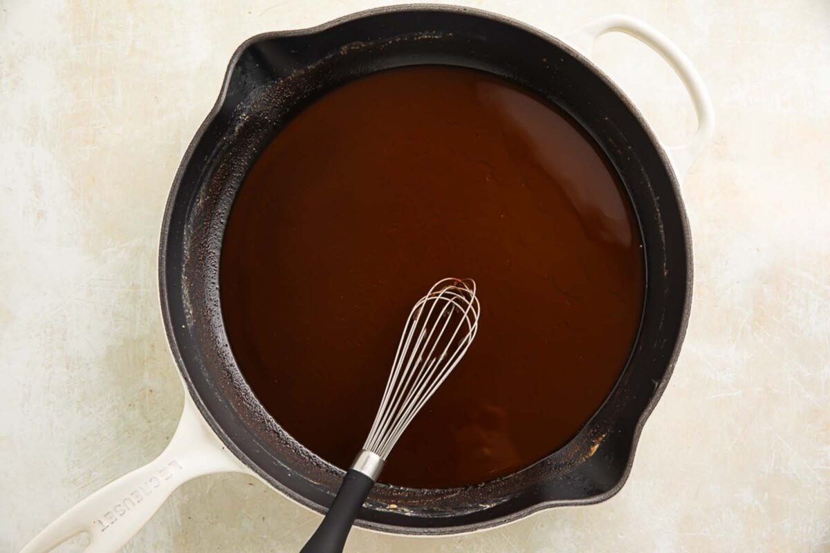 A rich, dark brown Cajun gumbo roux in a large skillet with a whisk.