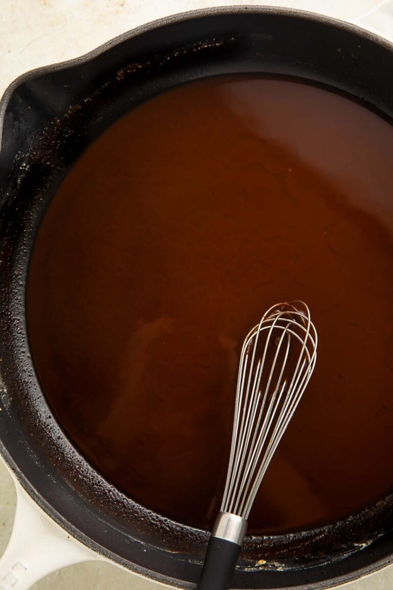 A rich, dark brown Cajun gumbo roux in a large skillet with a whisk.