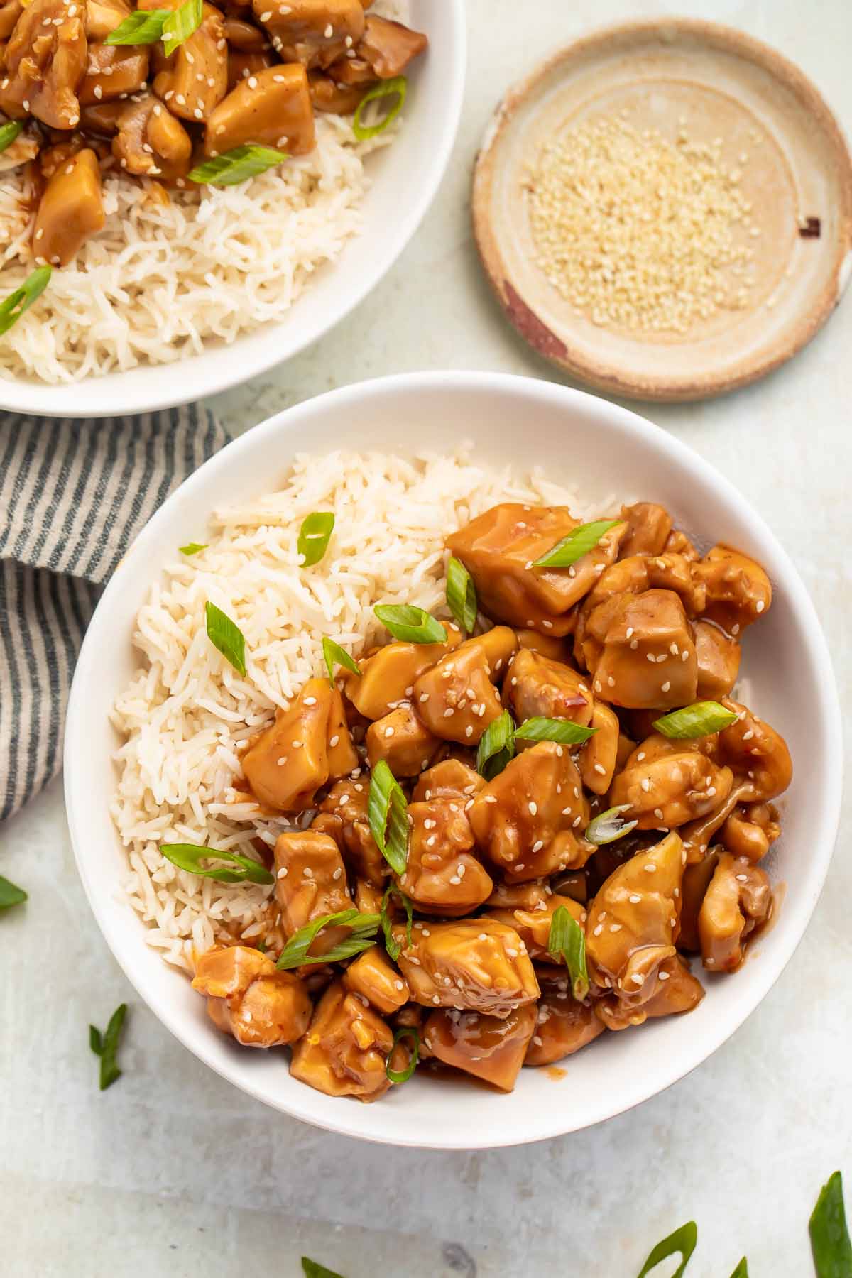 Overhead photo of a bowl of Instant Pot bourbon chicken with white rice garnished with sliced green onions.