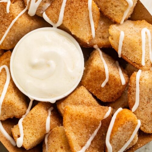 Close-up of a cardboard tray holding keto cinnamon roll bites (made from keto buns) with a cream cheese icing.