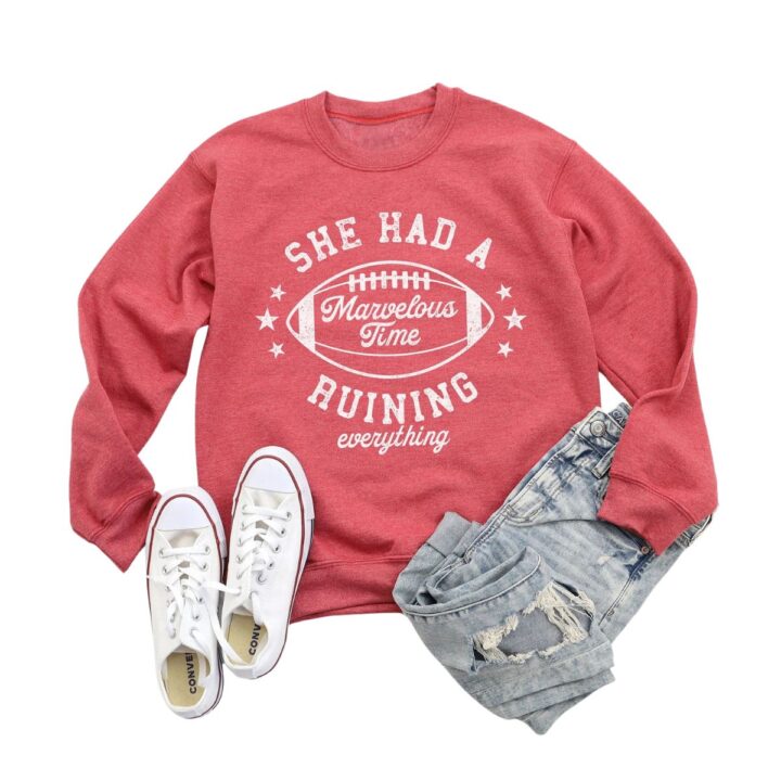 Red "She had a marvelous time ruining everything" sweatshirt flatlay.