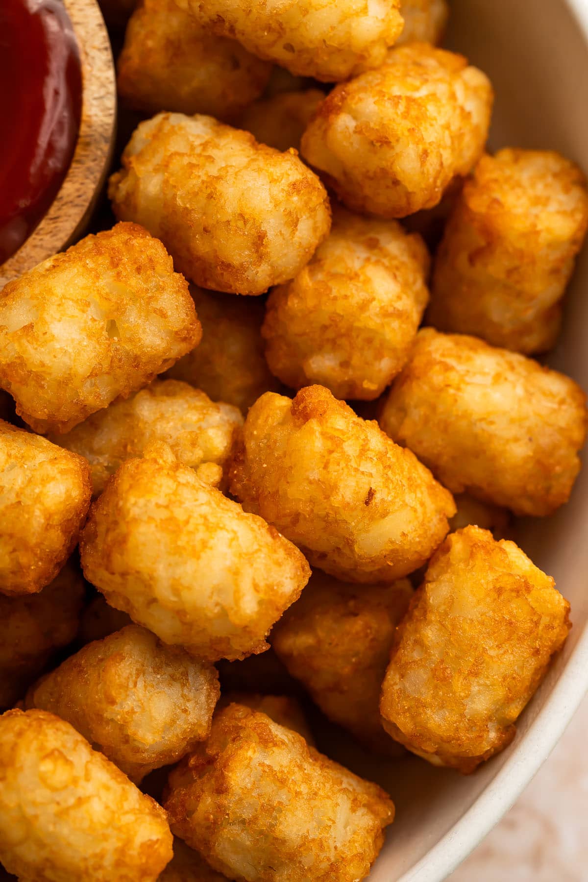 Close-up of air fryer tater tots in an air fryer basket.