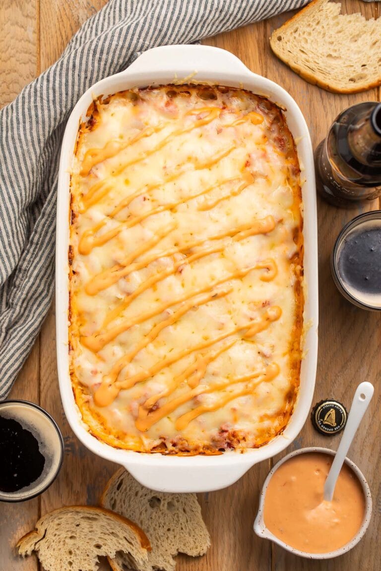 Overhead photo of a Reuben casserole on a table, surrounded by Russian dressing and sauerkraut.