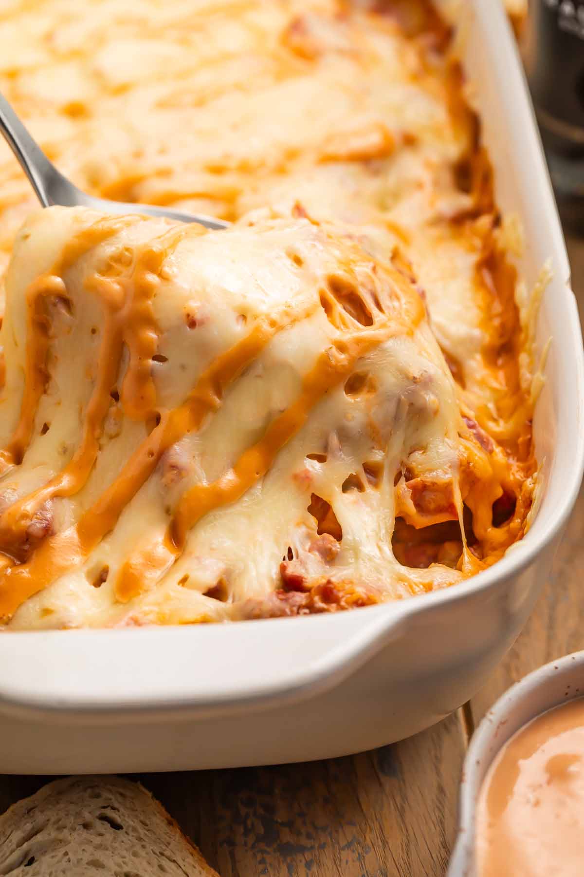 A scoop of Reuben casserole being lifted out of a casserole dish.