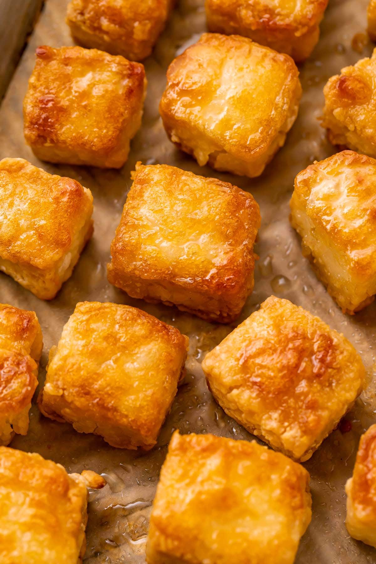 Crispy baked tofu cubes arranged on a baking sheet next.