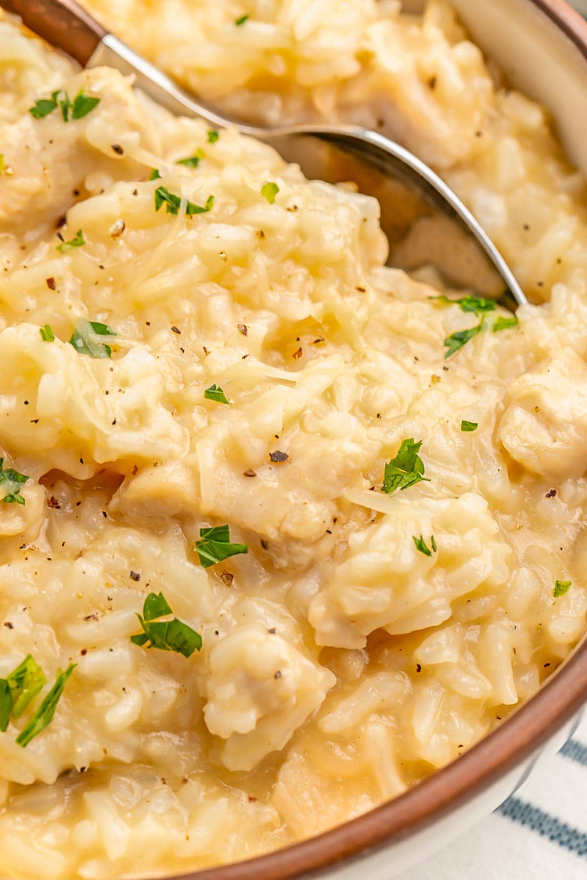 Close-up of Instant Pot chicken and rice in a bowl with a silver spoon.