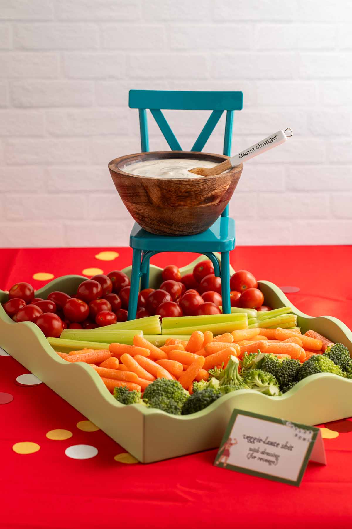 A rectangular green serving tray with scalloped edges holds an arrangement of fresh vegetables