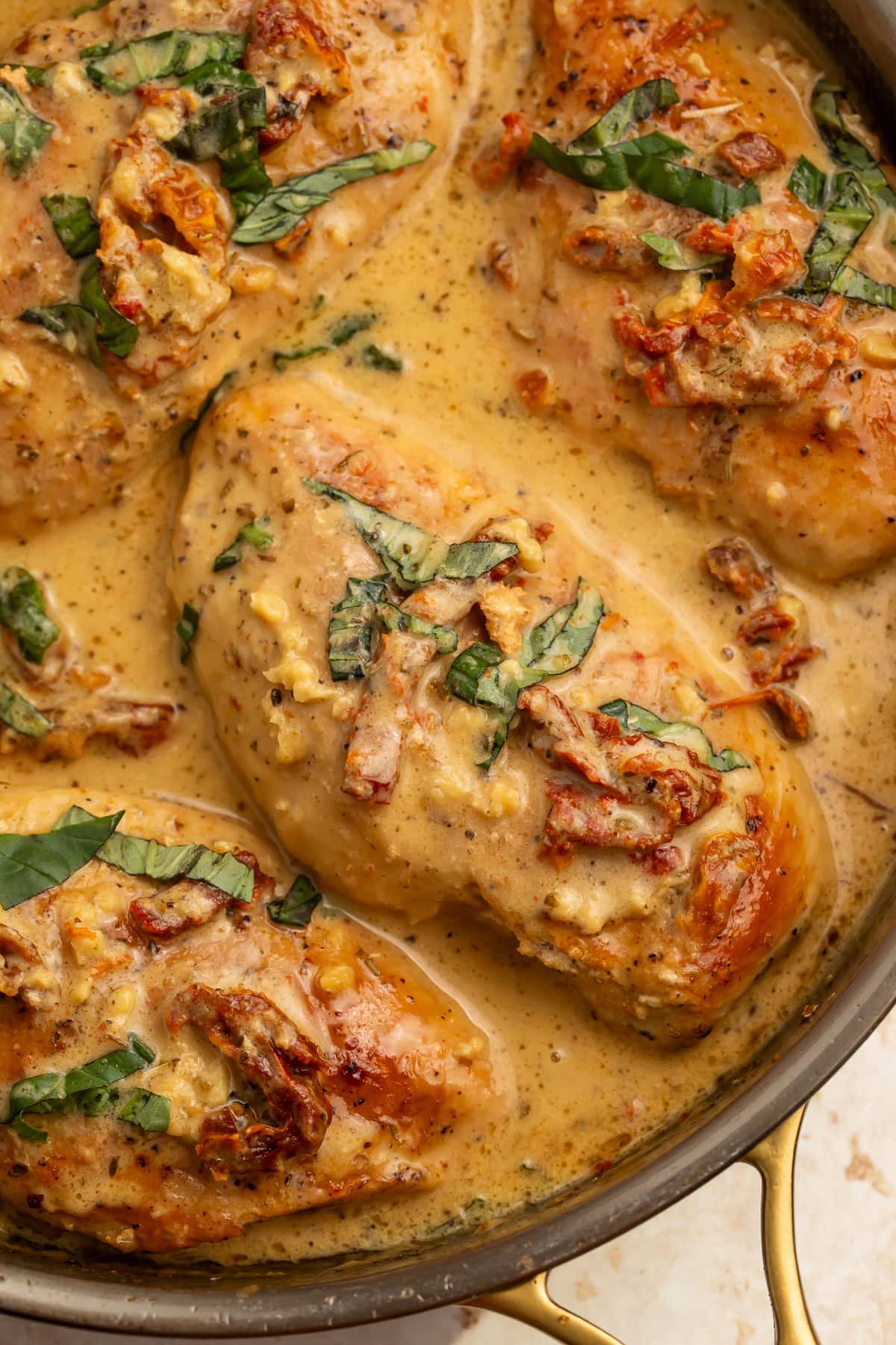 Whole30 marry me chicken in cast iron skillet with creamy coconut sauce, sun-dried tomatoes, and fresh basil.