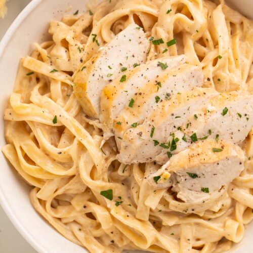 Close-up of Instant Pot chicken alfredo in a large white bowl on a table.