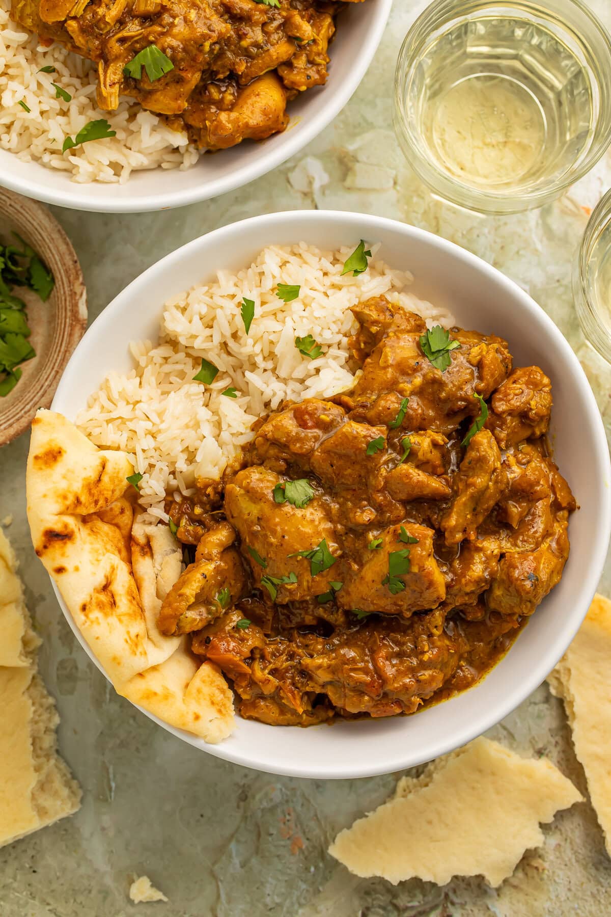 Restaurant-style chicken curry served over basmati rice with naan in a white bowl