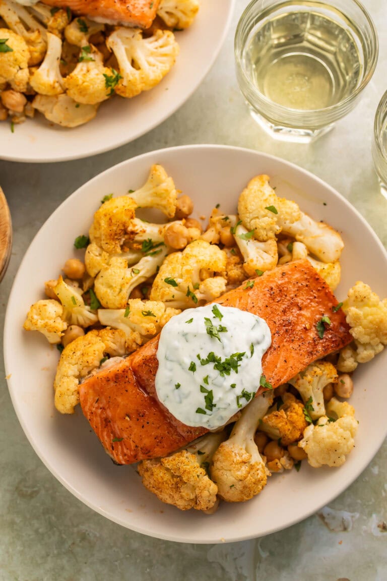 A bowl of sheet pan salmon and cauliflower with hot honey and yogurt sauce.