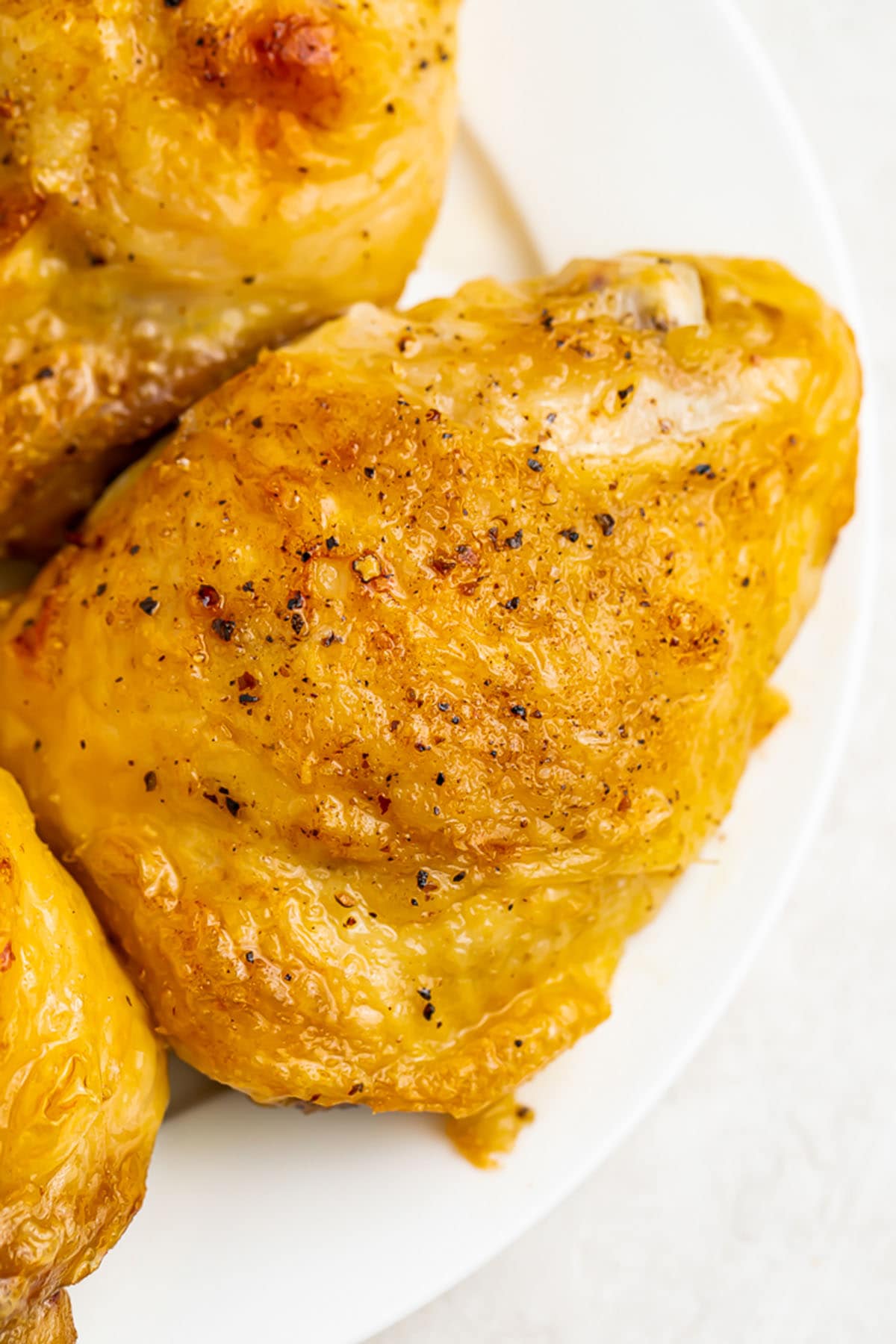 Fully cooked Instant Pot frozen chicken thighs on a round white plate.