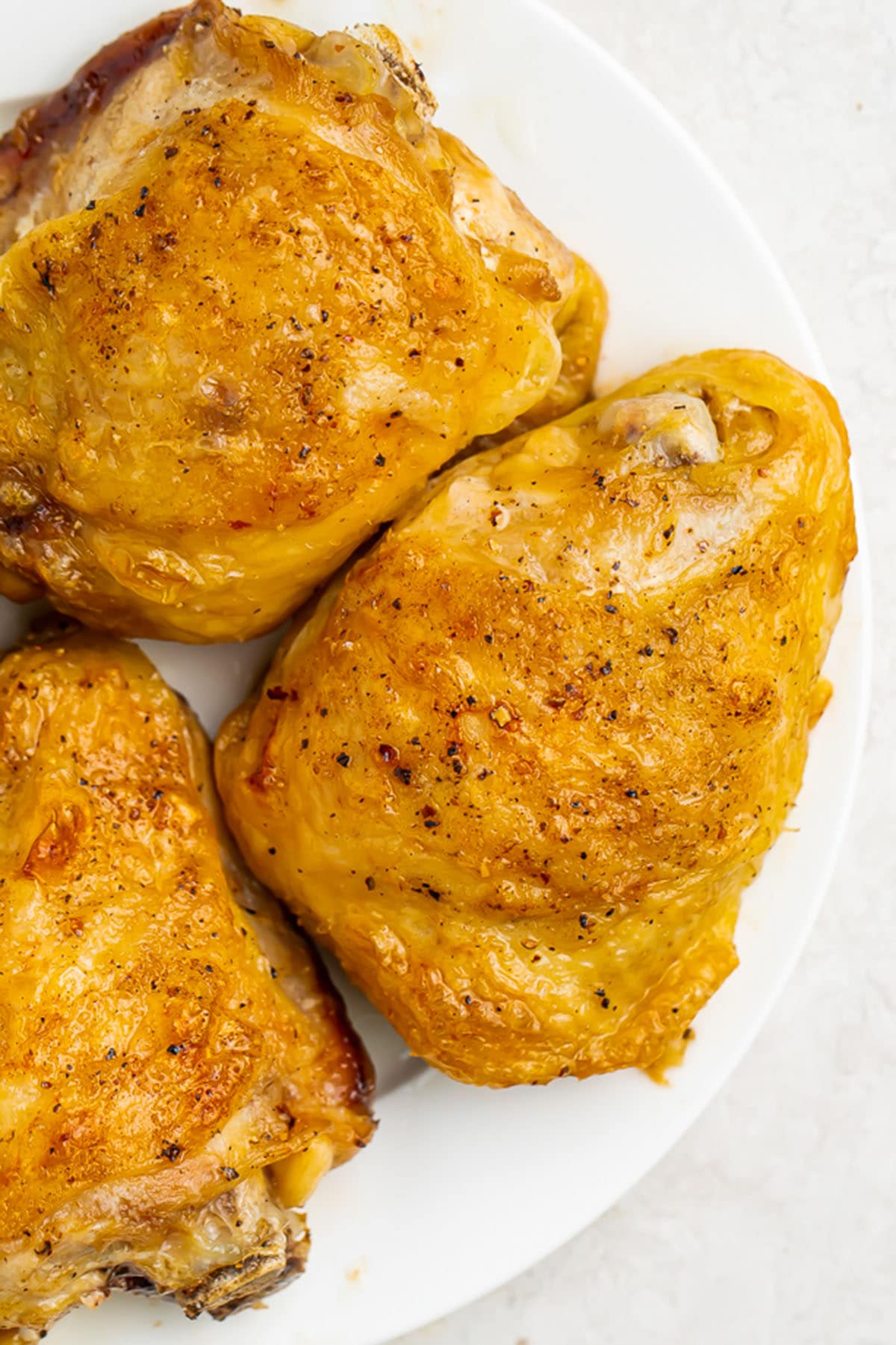 Fully cooked Instant Pot frozen chicken thighs on a round white plate.