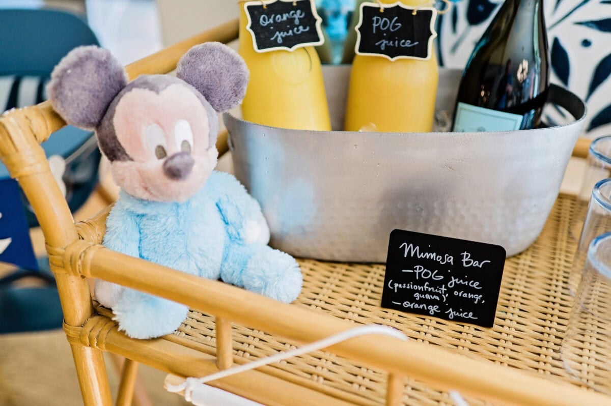 A mimosa bar on a rattan cart themed for a Magic Kingdom birthday party.