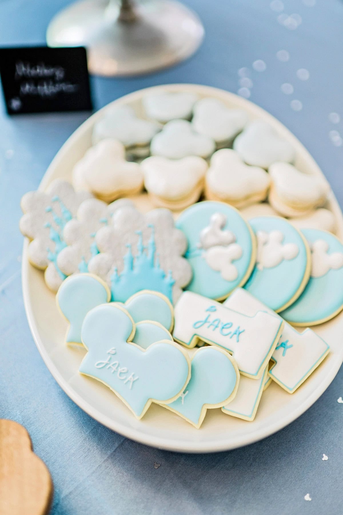 A platter of light blue, silver, and white decorated cookies and macarons.