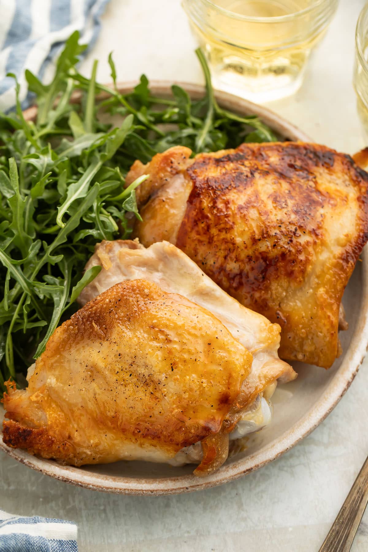 Two perfect crispy chicken thighs plated with a leafy green side salad.