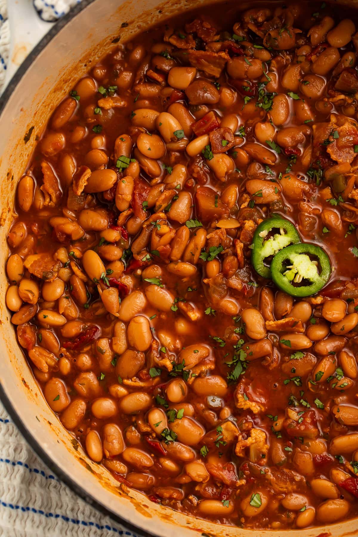 A large pot of charro beans topped with 2 jalapeño slices.