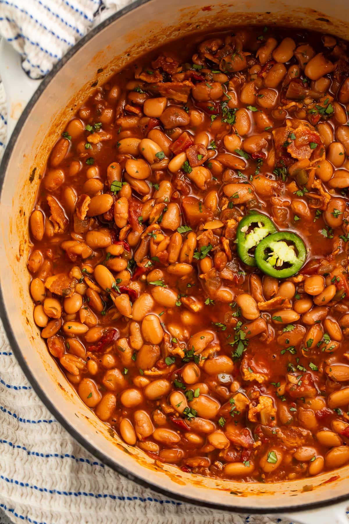 A large pot of charro beans topped with 2 jalapeño slices.
