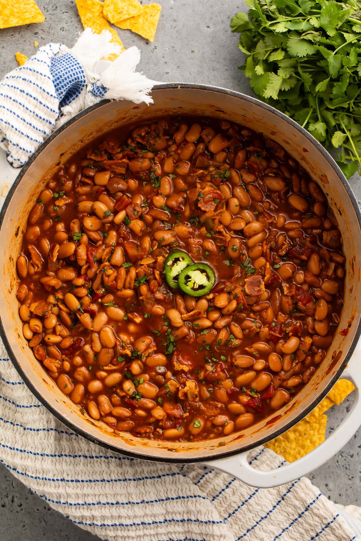 A large pot of charro beans topped with 2 jalapeño slices.