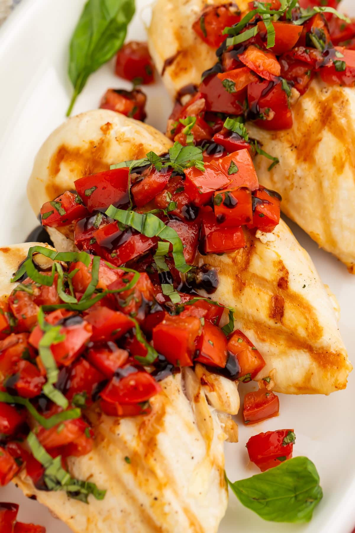 Close up of bruschetta chicken breasts sprinkled with sliced basil. 