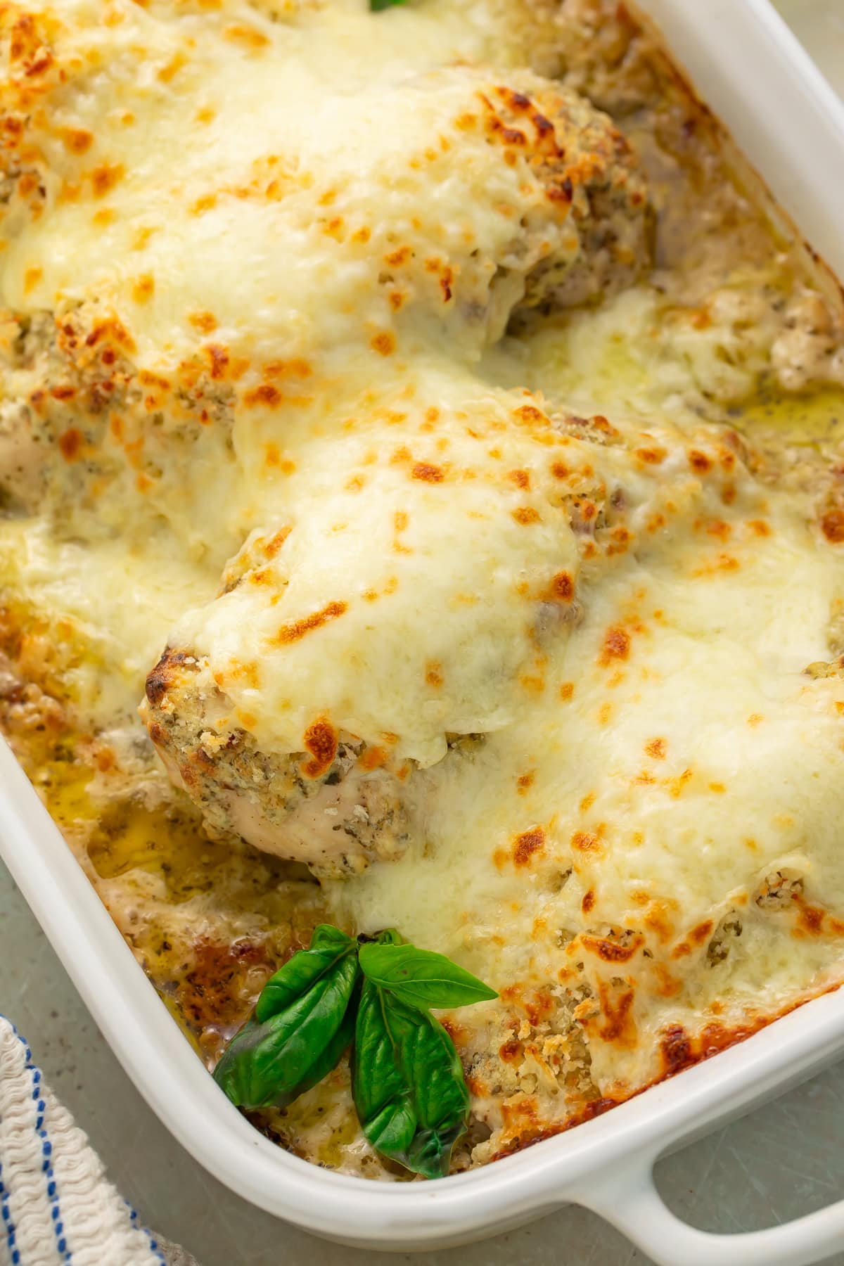 Bowl of creamy pesto mixture with green herbs swirled into softened cream cheese