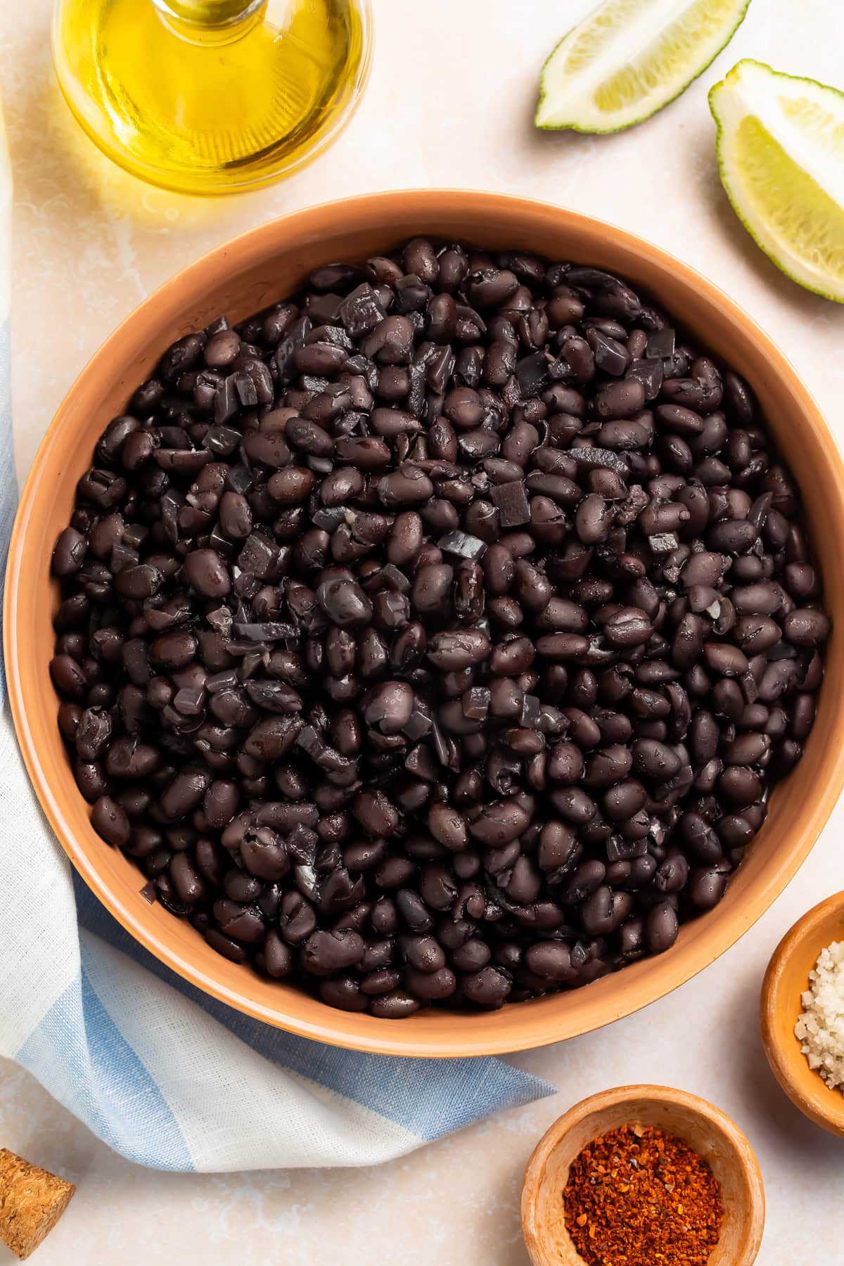 Cooked black beans in terra cotta bowl with lime wedges and olive oil