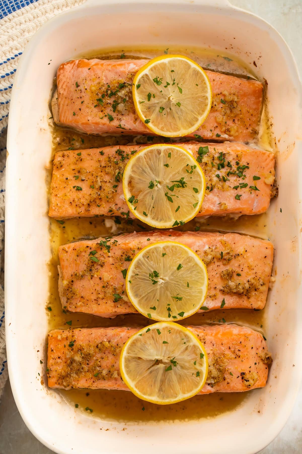 Baked salmon fillet being cut with fork showing flaky interior