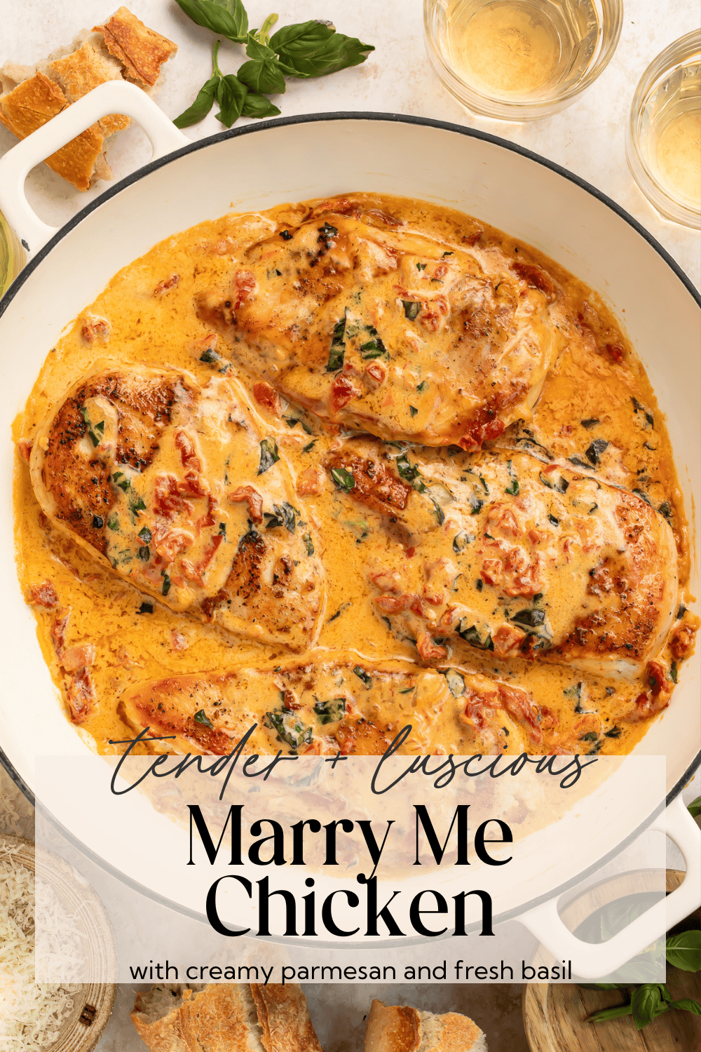 Overhead view of complete dinner with chicken in sauce, wine glasses, and fresh herbs