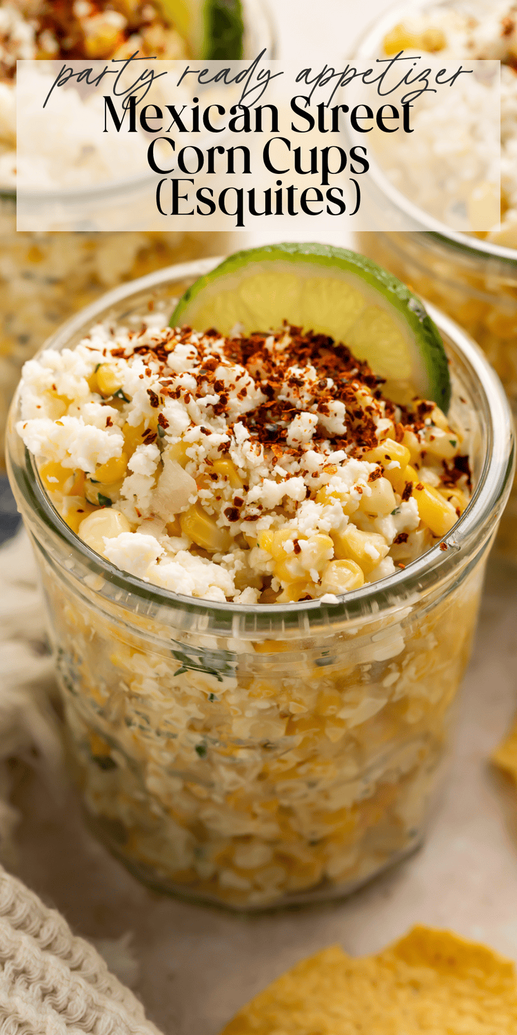 Close-up of corn mixture topped with crumbled cheese and chili powder in clear jar"