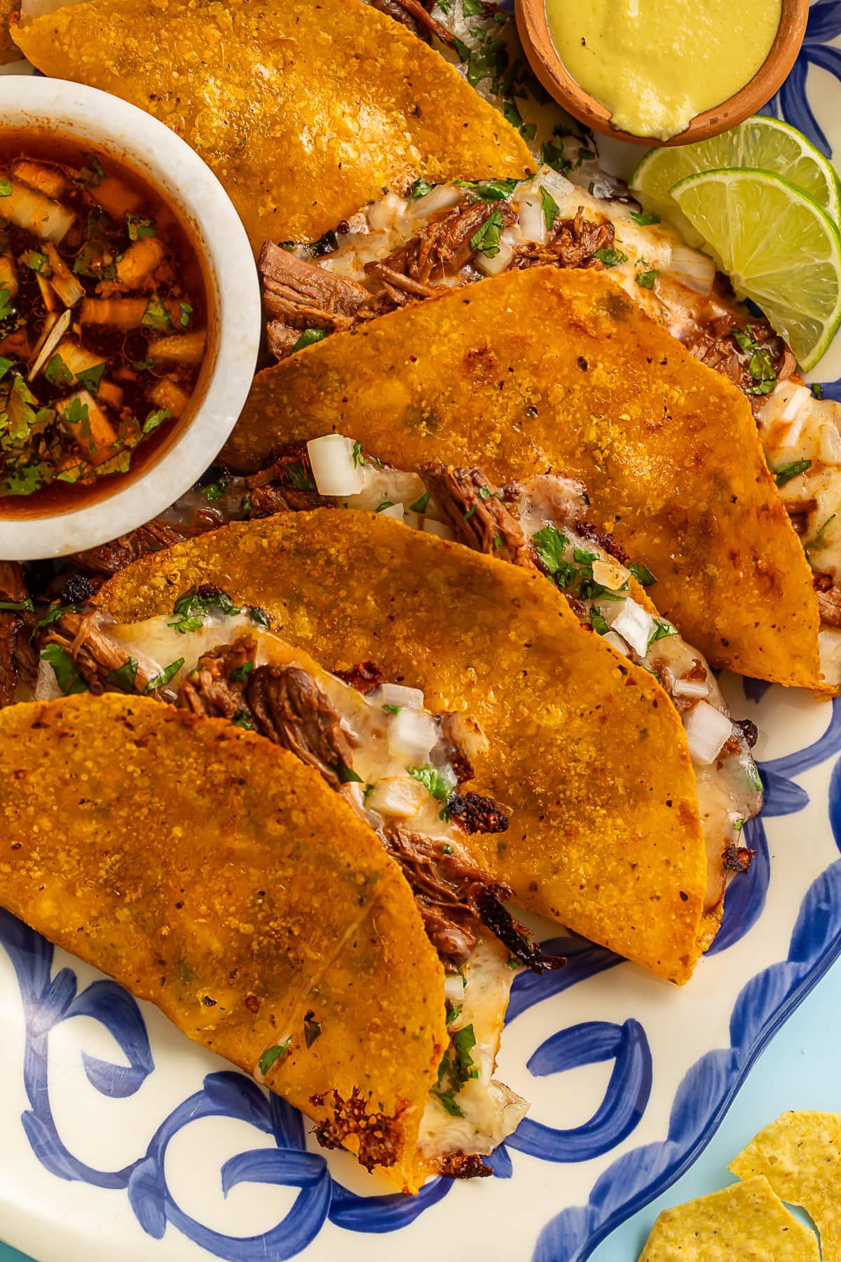 Crispy quesabirria tacos with perfectly melted cheese and tender shredded birria beef, served with rich consommé for dipping. The golden-brown tortillas are beautifully charred and stuffed with savory meat and cheese.