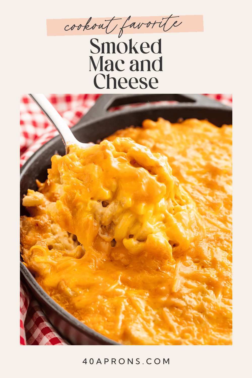 Creamy smoked mac and cheese in a cast iron skillet with a spoon lifting a portion showing the melted cheese texture