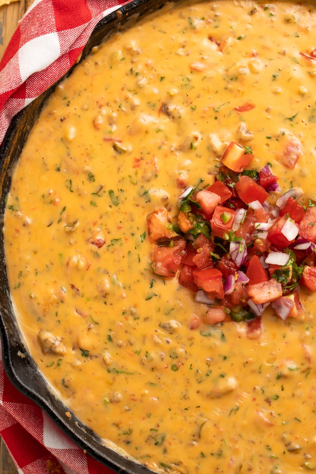 Creamy smoked queso dip with melted cheese and sausage in a cast iron skillet, garnished with fresh cilantro