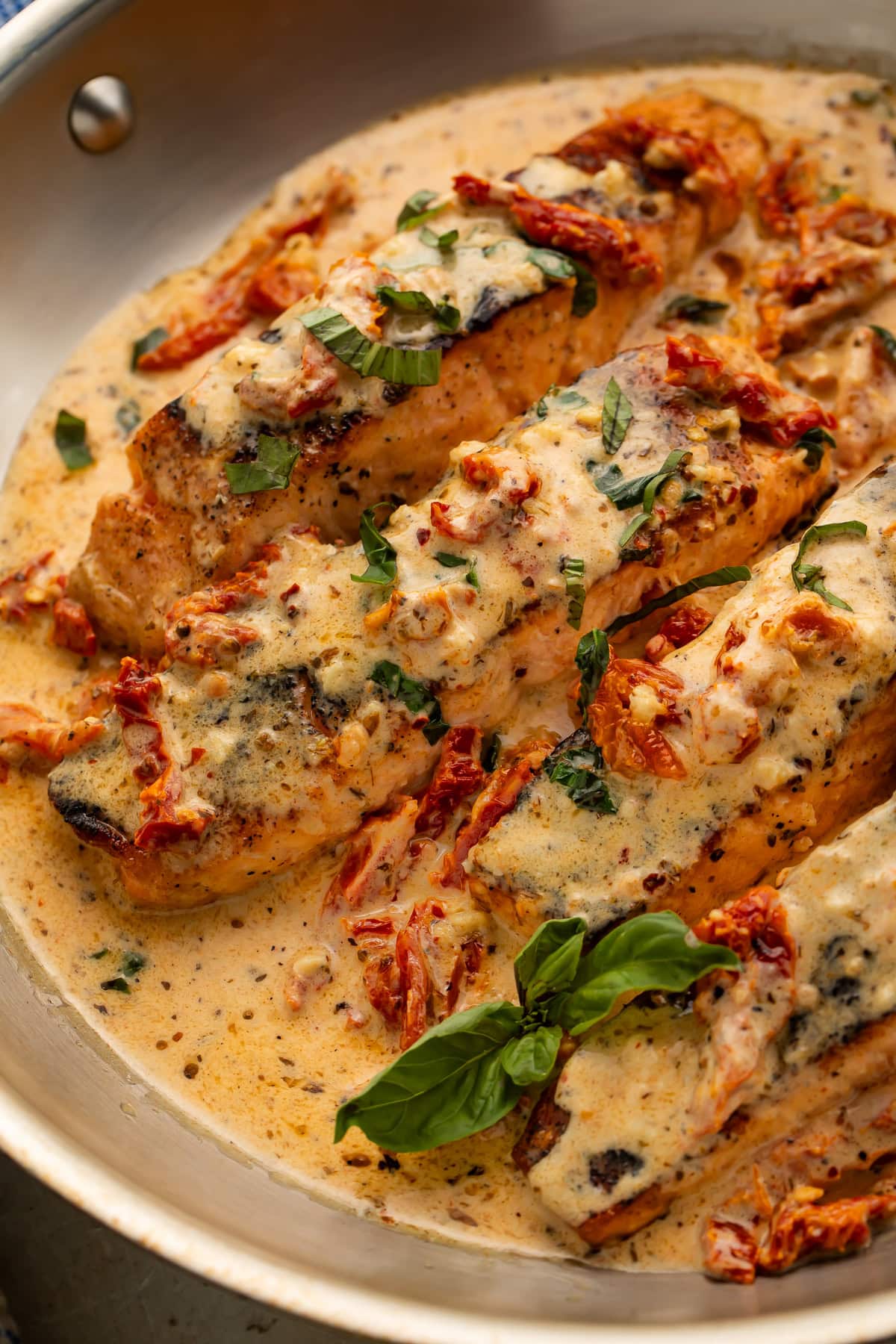 Close-up of marry me salmon with melted parmesan cream sauce and fresh basil garnish