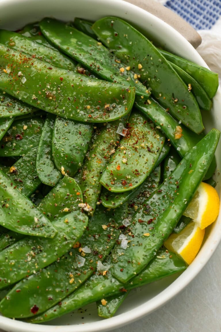Overhead view of finished garlic butter snow peas with visible seasoning and herbs
